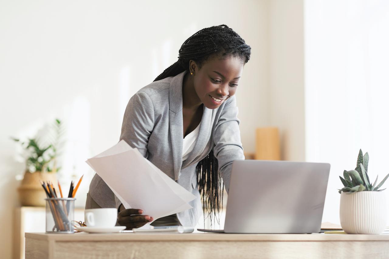 Secrétaire noire, féminisme économique africain, occupée prenant des notes debout près de son bureau